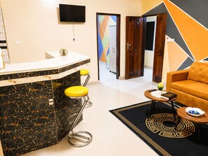 Una sala de estar moderna con un sofá, una mesa de centro y una zona de bar con taburetes.