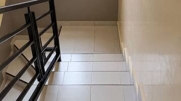 Una escalera con un extintor en la pared, un ventanal y una barandilla metálica.