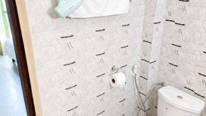 Ein Badezimmer mit Toilette, Handtuchhalter, Duschkopf und Toilettenpapierhalter.