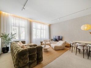 Ein modernes Wohnzimmer mit einem Ecksofa, einem runden Couchtisch und einem Fernseher.