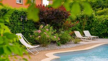 A pool area with two lounge chairs and a variety of plants.