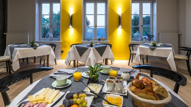 Ein Frühstücksbuffet mit Tischen, Stühlen und einer Auswahl an Speisen, darunter Obst, Käse und Gebäck.