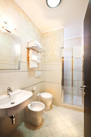 Une salle de bain moderne équipée d’un lavabo, d’un bidet, de toilettes et d’une douche à parois de verre.