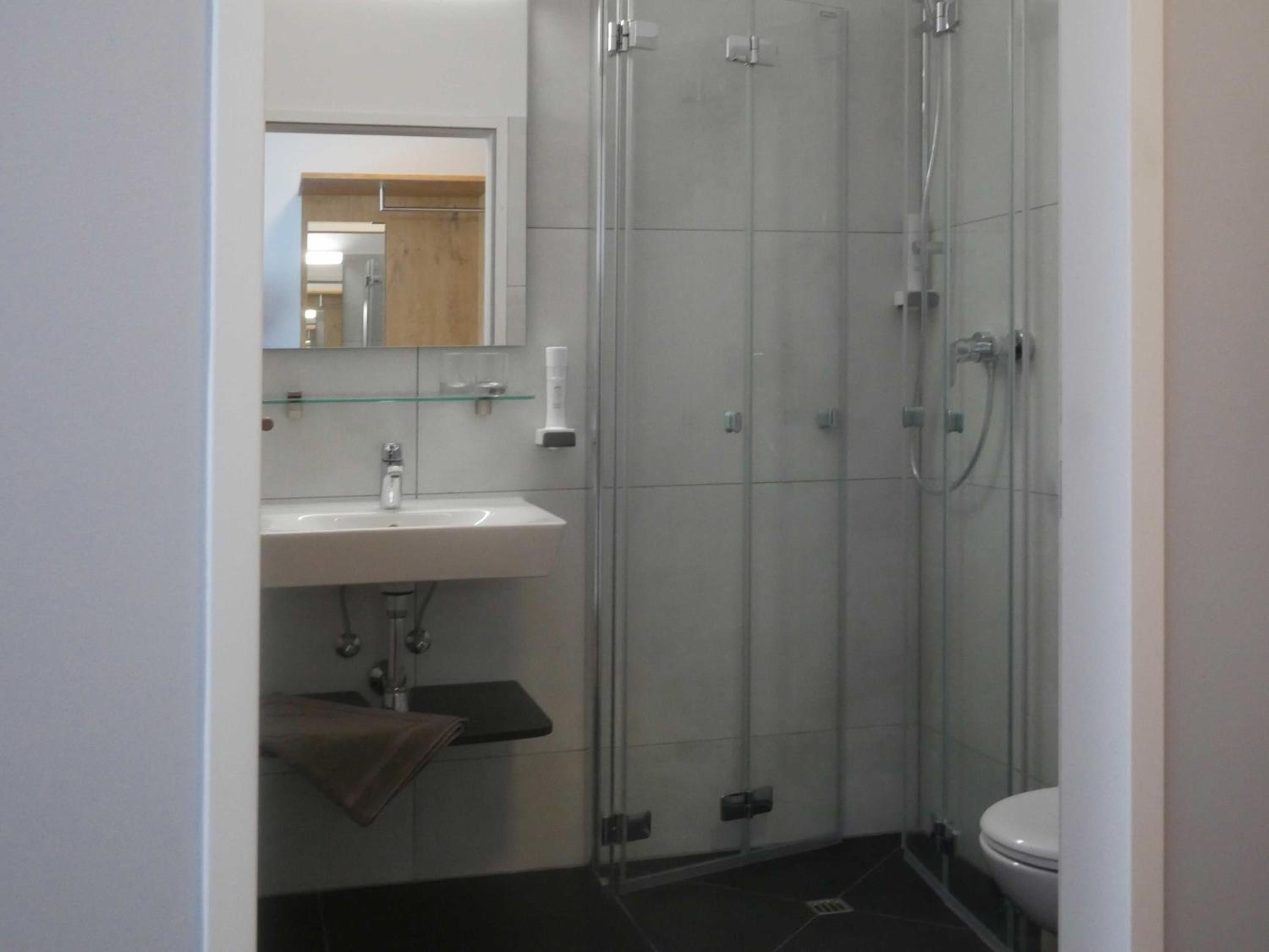 A bathroom with a glass-enclosed shower, a white sink, and a toilet.