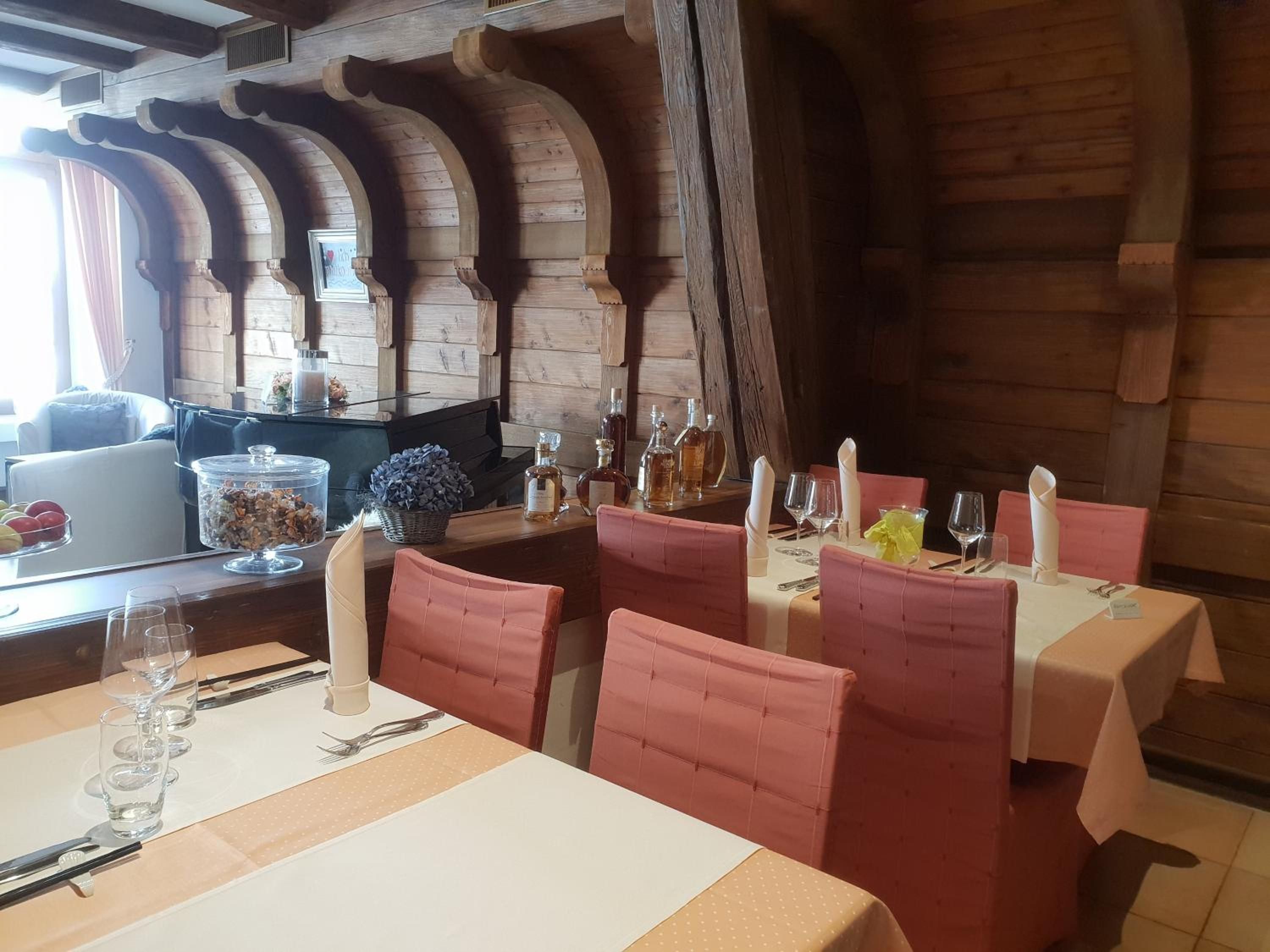 Un comedor con vigas de madera, sillas tapizadas en rosa y una mesa preparada para una comida.