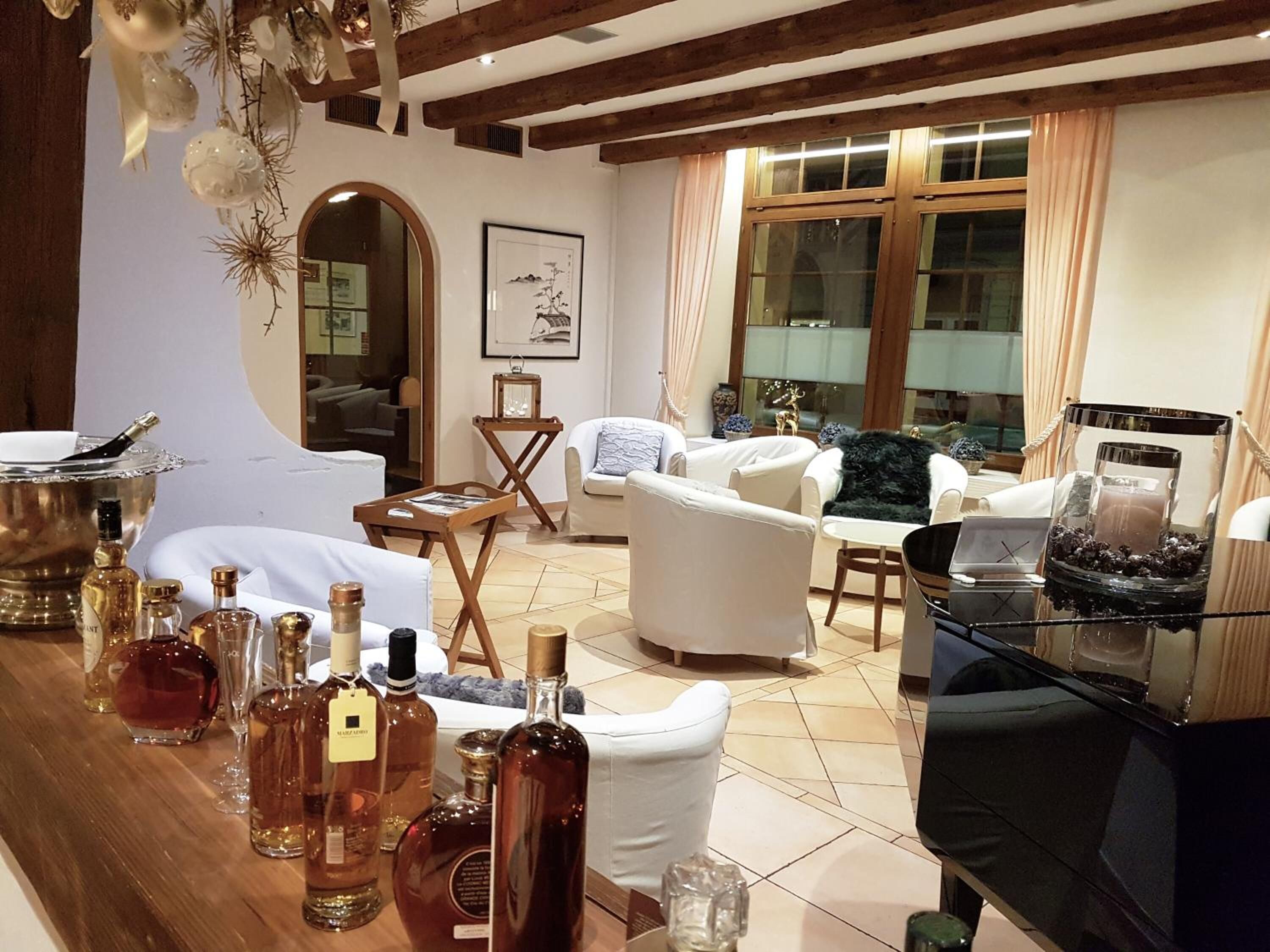 A living room with a fireplace, white sofas, a coffee table, and a bar area with bottles.