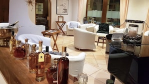 A living room with a fireplace, white sofas, a coffee table, and a bar area with bottles.