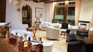 A living room with a fireplace, white sofas, a coffee table, and a bar area with bottles.