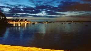 Vista al frente del agua con un muelle que se extiende hacia aguas tranquilas, una costa distante y un cielo despejado.