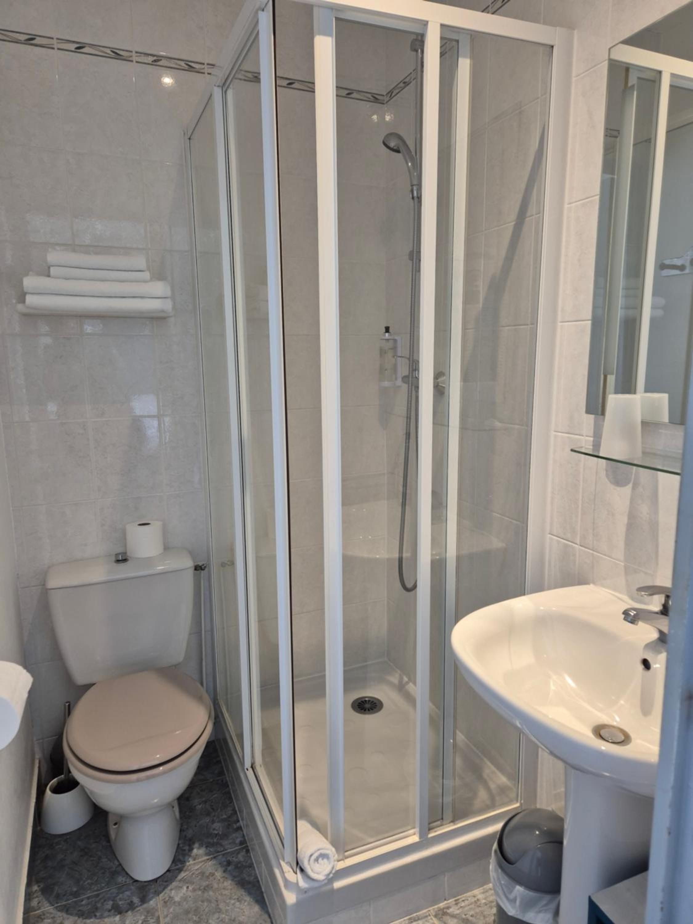 Une salle de bain moderne avec une douche à parois de verre, des toilettes et un lavabo.