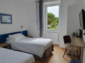 A hotel room with two beds, a desk with a chair, a television, and a window with curtains. - Hôtel Glann Ar Mor (Arzon)
