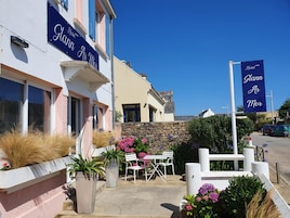 A hotel named 'Glann Ar Mor' with a stone wall, outdoor seating, and potted plants.