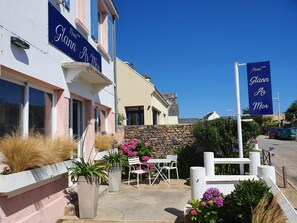 A hotel named 'Glann Ar Mor' with a stone wall, outdoor seating, and potted plants. - Hôtel Glann Ar Mor (Arzon)