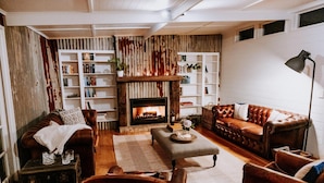 A cozy living room with a fireplace, leather sofas, a coffee table, and bookshelves. - The Homestead (Berry)