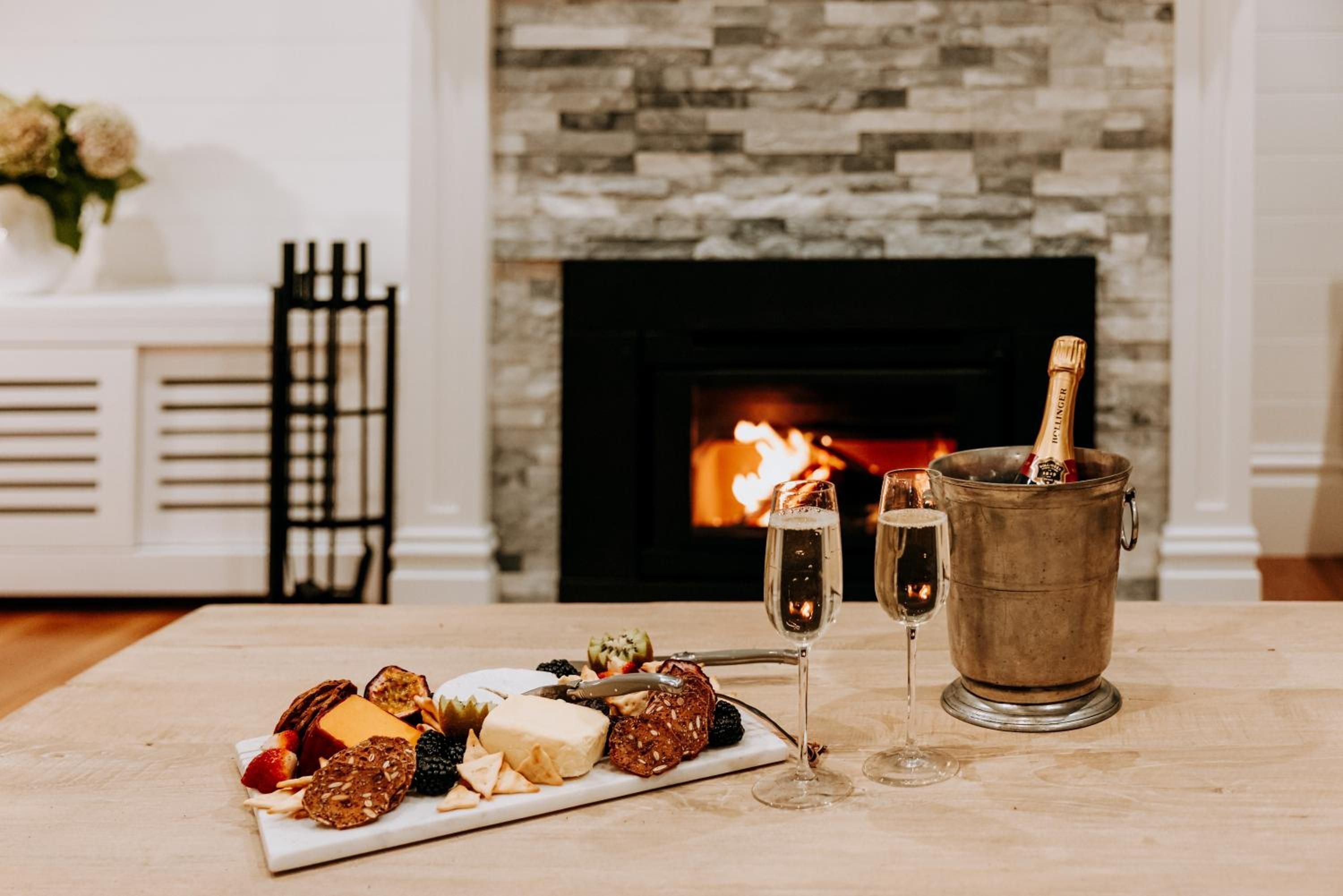 A table with a charcuterie board, two champagne flutes, and a champagne bottle in a bucket.