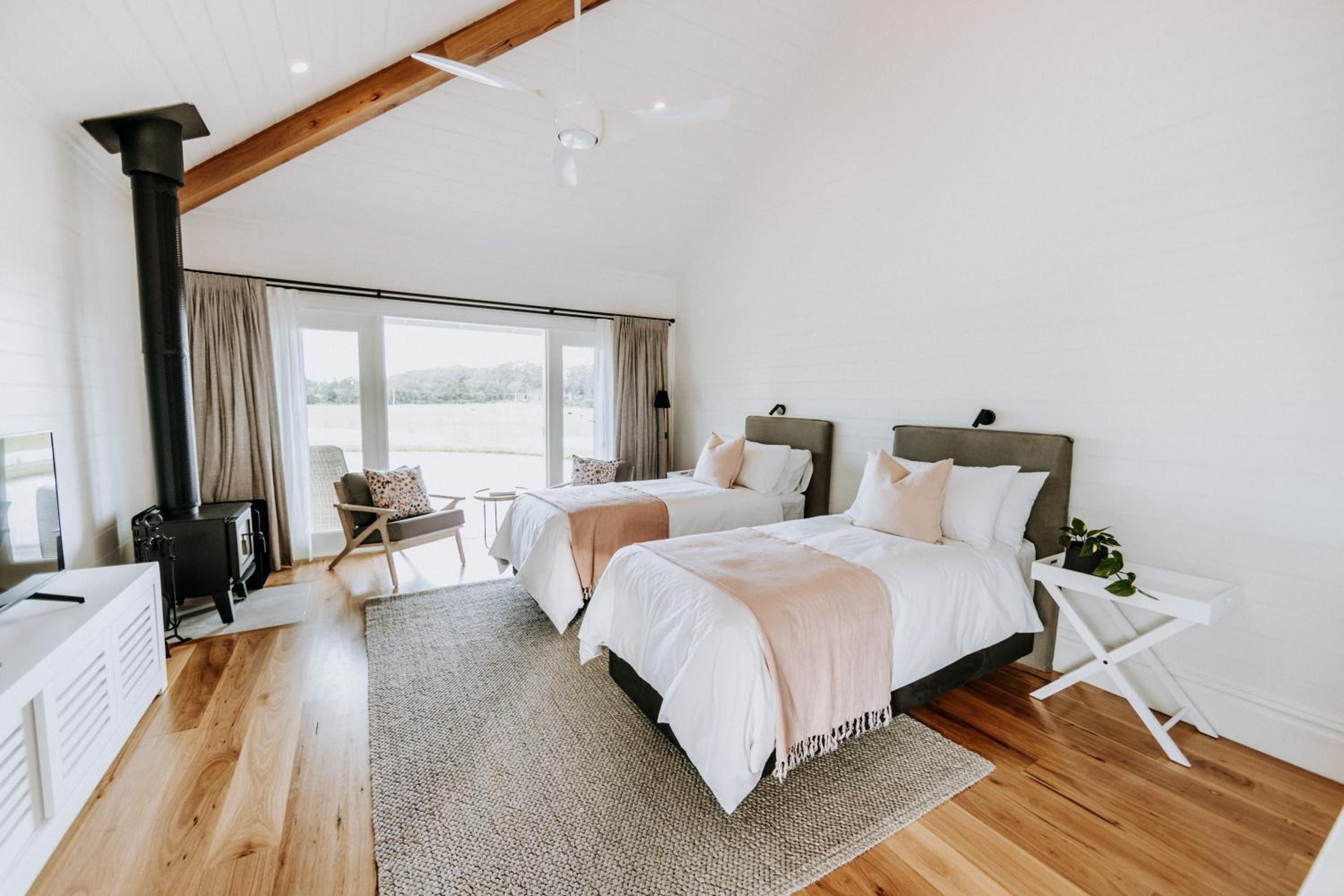 A bedroom with two beds, a large window, and a view of the outdoors.