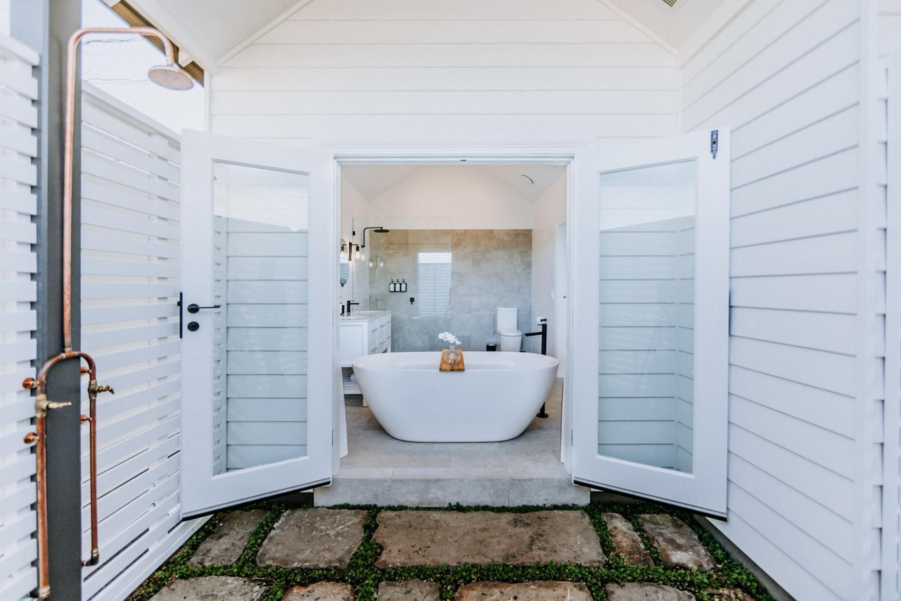 A modern bathroom with a freestanding bathtub, a shower, and a vanity with a mirror.