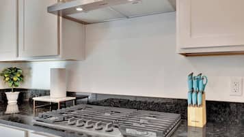 Une cuisine moderne dotée d’une cuisinière à gaz, de meubles blancs et d’un plan de travail en marbre.