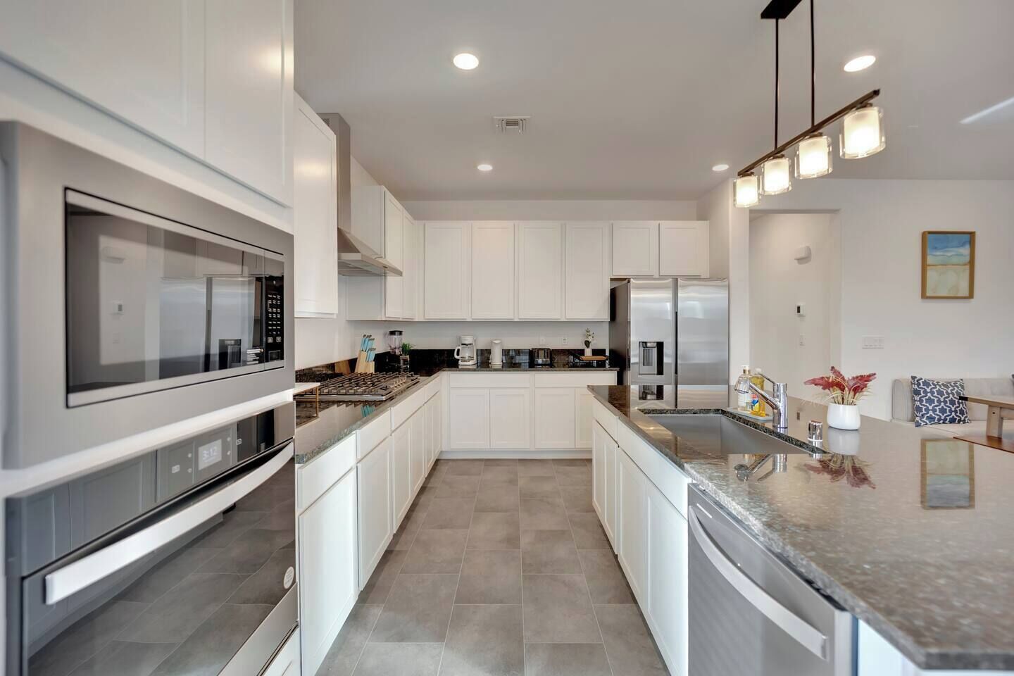 Una cocina moderna con armarios blancos, electrodomésticos de acero inoxidable y encimera de granito.