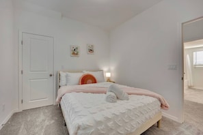 Une chambre à coucher avec un lit, une porte et une table de chevet avec une lampe.