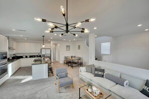 A modern kitchen with white cabinets, a central island, and a dining area with a wooden table and chairs. - 2700SF Modern 5B3B｜Near Strip｜Fiber WiFi｜King Bed (Las Vegas)