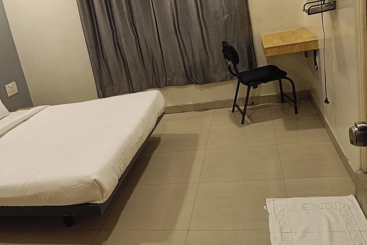 Een hotelkamer met een bed, een stoel, een bureau en een deur.