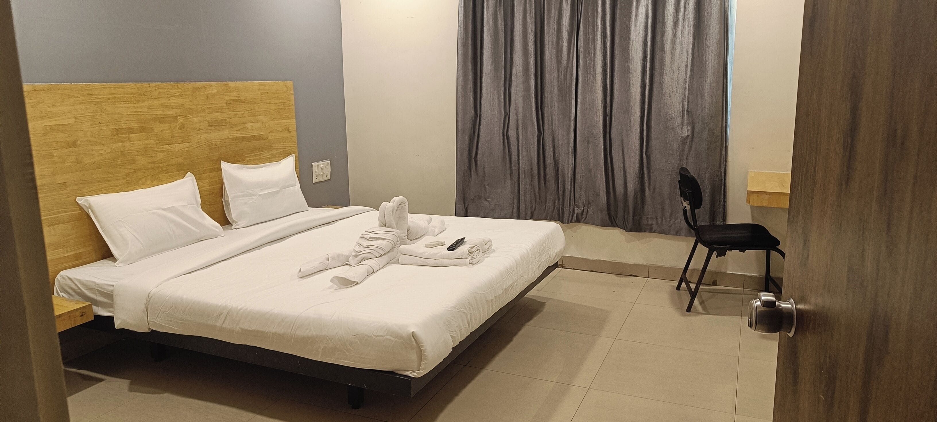 A hotel room with a bed, a chair, and a door.