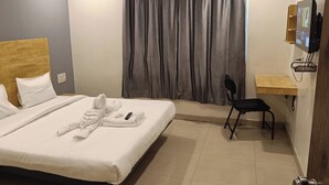 Une chambre d’hôtel avec un lit, un bureau, une chaise et un téléviseur.