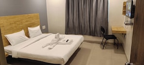 Een hotelkamer met een bed, een bureau, een stoel en een televisie.