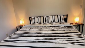 Uma cama com colcha listrada em padrão de zebra, duas luminárias de cabeceira e uma mesa de cabeceira com abajur.