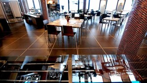 Un restaurant spacieux, doté de nombreuses tables et chaises, de grandes fenêtres et d’un aménagement intérieur moderne.