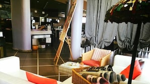 Un espace détente moderne avec un canapé blanc, une petite table d’appoint en osier et un lampadaire.