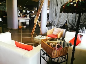 A modern lounge area with a white sofa, a wicker side table, and a floor lamp. - Albergo Delle Industrie (Casalmaggiore)