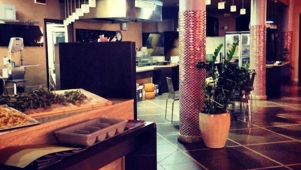 Un espace intérieur vaste, doté d’un long comptoir, d’une plante en pot et d’un escalier menant à un niveau supérieur.
