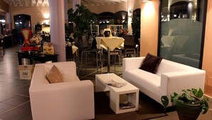 Un espace détente moderne avec des canapés blancs, une table basse et une plante en pot.