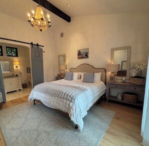A bedroom with a large bed, bedside tables, a chandelier, and a dresser. - 2-bedroom Guest House European estate in  Somis perfect for relaxing getaway (Somis)