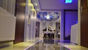 A hotel room with a glass partition, a ceiling with a cloud design, and a dining area with a table and chairs. - Hotel Imperium (Pionki)