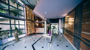 A hotel lobby with a modern design, featuring a reception desk, a staircase, and a large window offering a view of the outdoors. - Hotel Imperium (Pionki)