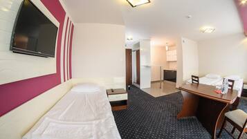 Habitación de hotel con cama, escritorio, silla, pequeña mesa, espejo y televisor.