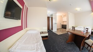 A hotel room with a bed, a desk, a chair, a small table, a mirror, and a TV. - Hotel Imperium (Pionki)