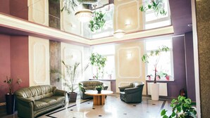 A spacious lobby with a high ceiling, multiple seating areas, and large windows allowing natural light. - Hotel Imperium (Pionki)