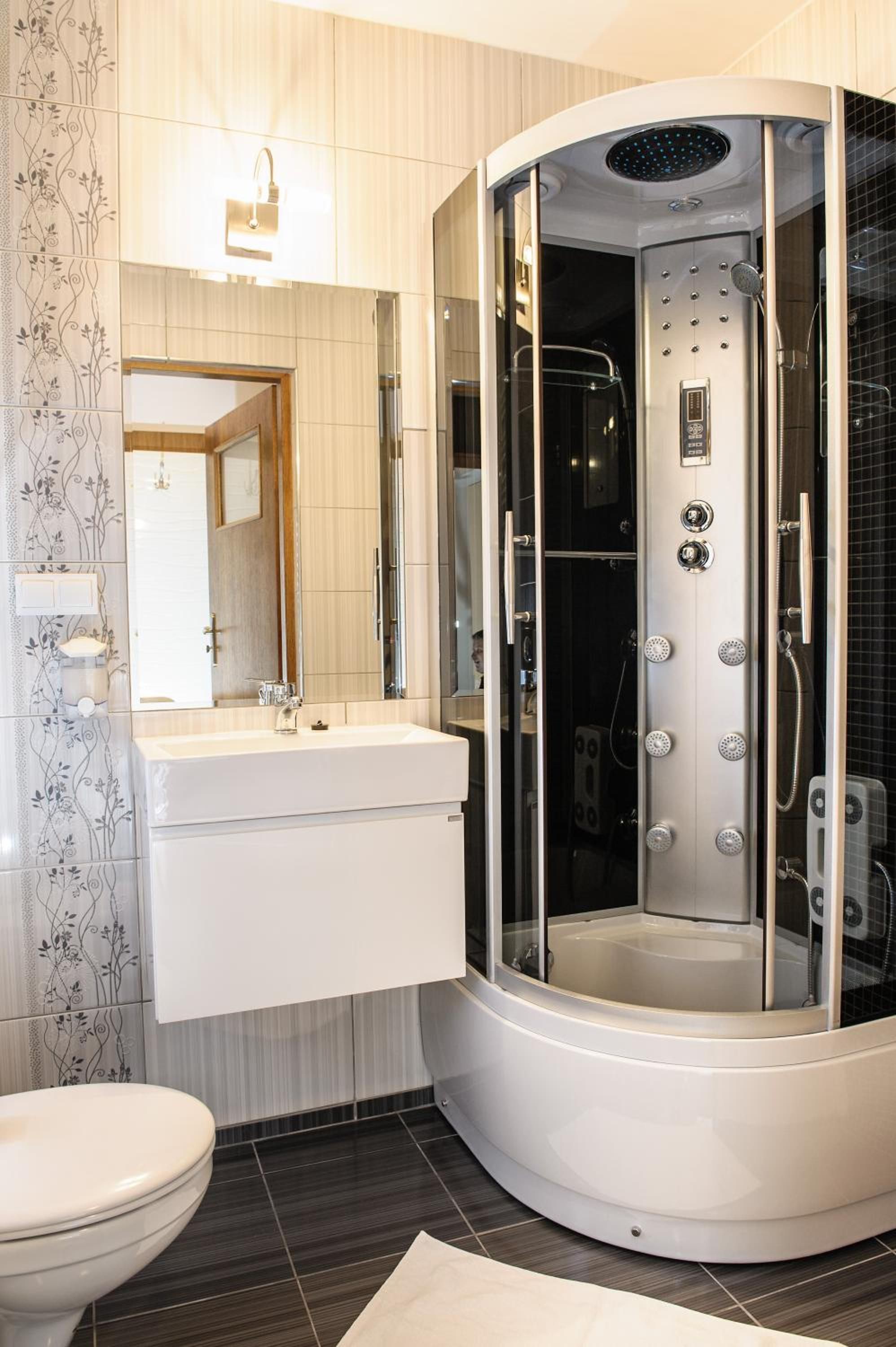 A modern bathroom with a curved shower enclosure, a vanity with a mirror, and a toilet.