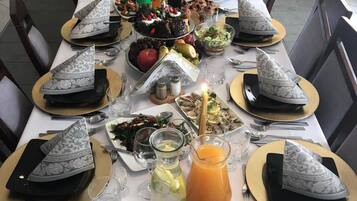 A long dining table set with multiple place settings, including plates, cutlery, and various food items.