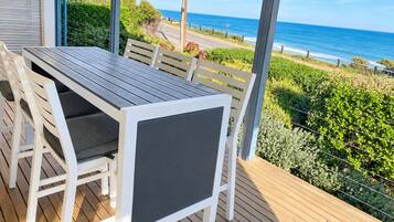 A covered outdoor seating area with a view of the ocean.