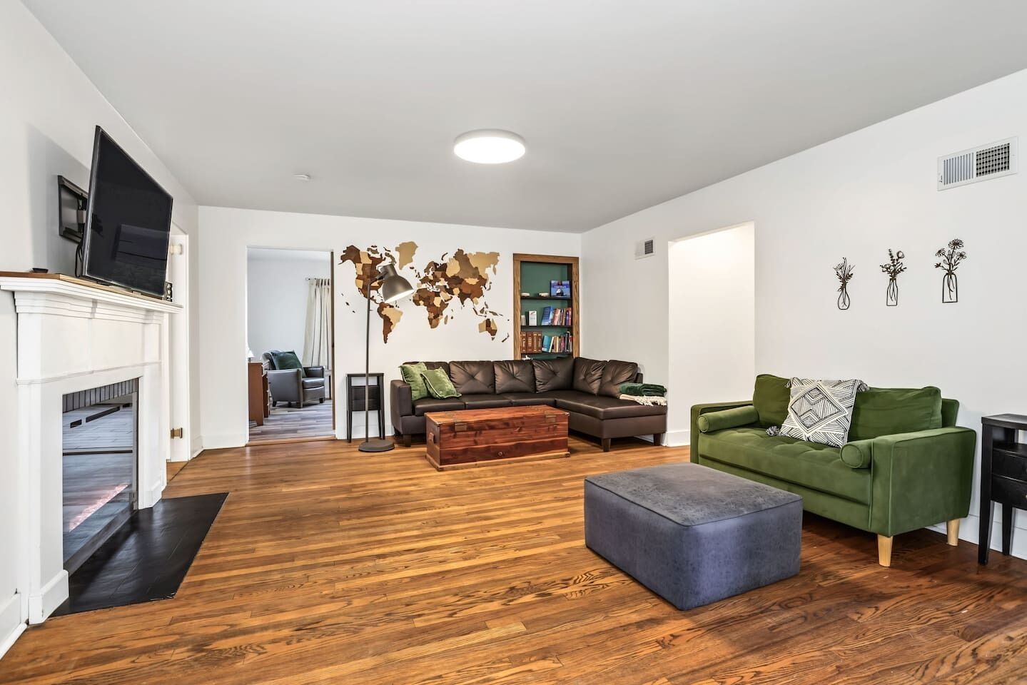 A modern living room with a fireplace, leather sofa, green armchair, and a world map wall decoration.