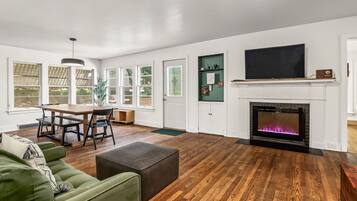 Ein Wohnzimmer mit Kamin, Essbereich und einem grünen Sofa.