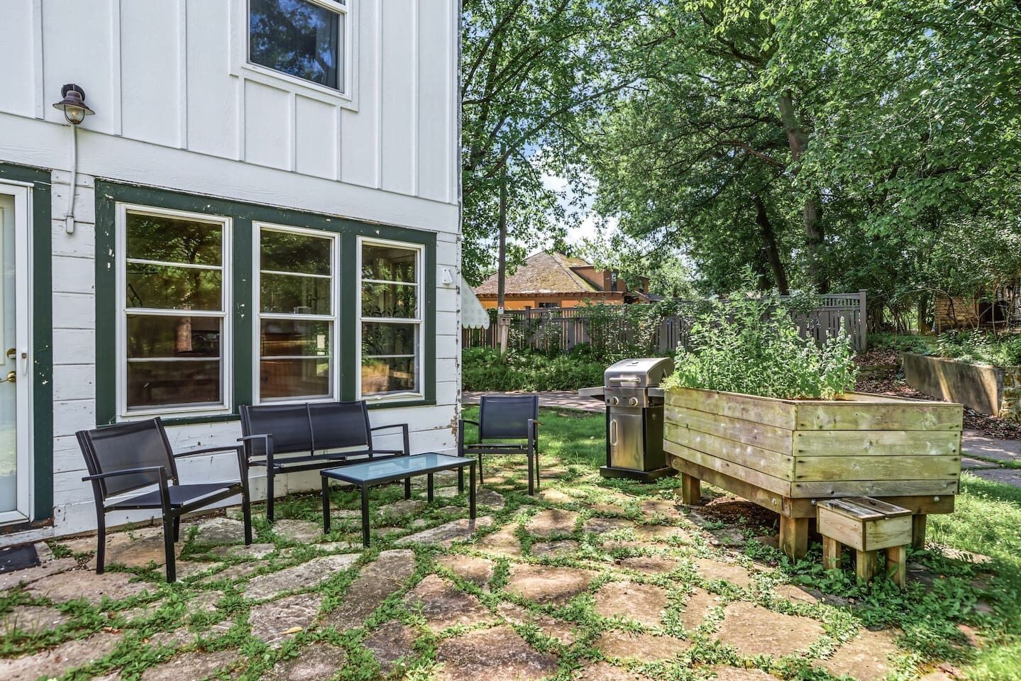 A patio with outdoor furniture, a wooden planter, and a grill.