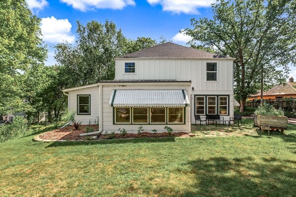 A two-story house with a covered front porch and a small garden area.