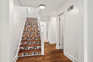 A staircase with a floral pattern, white walls, and wooden flooring.