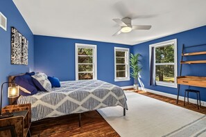 A bedroom with a bed, a ceiling fan, a window, a plant, and a desk with shelves. - Hilltop Charm — 4BR house in Menomonie (Menomonie)